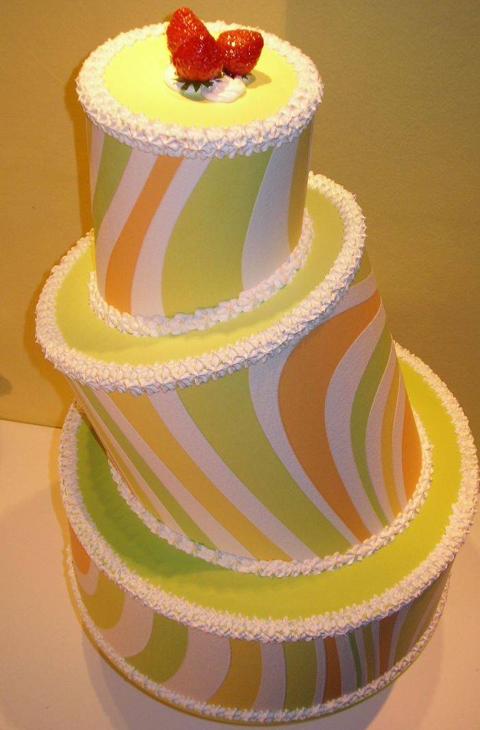 torta a tre piani con decorazioni geometriche, panna e fragole
