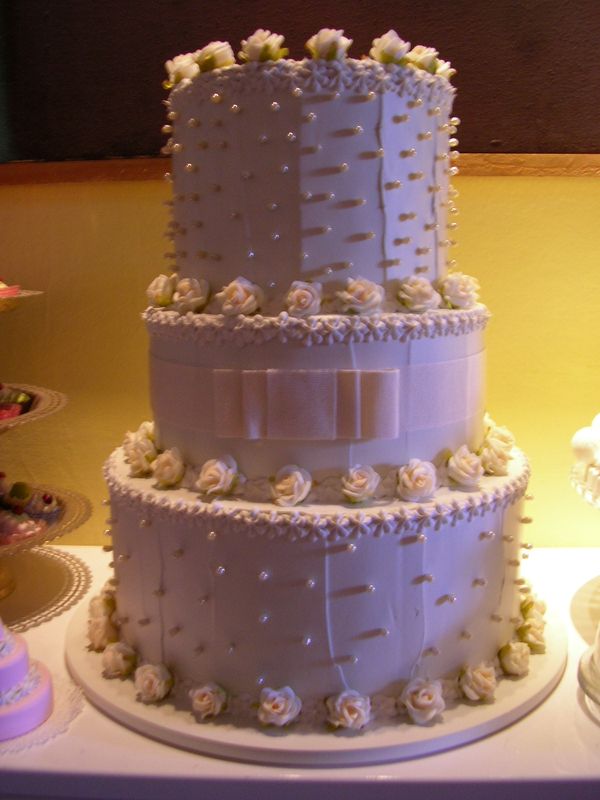 torta 3 piani bianca con roselline crema,  fiocco e perle